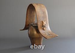 Old large pastoral cowbell with curved wooden collar and leather