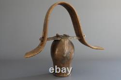 Old large pastoral cowbell with curved wooden collar and leather