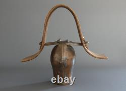 Old large pastoral cowbell with curved wooden collar and leather